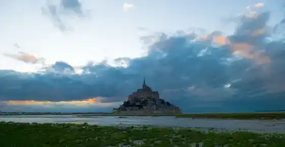Mont-Saint-Michel à marée basse sous un ciel dramatique